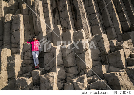 Traveler on hexagonal rocks in Vik, Iceland. 49973088