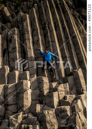 Traveler on hexagonal rocks in Vik, Iceland. 49973128