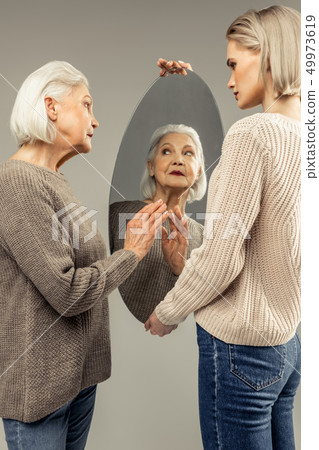 Nice good looking aged woman touching the mirror 49973619