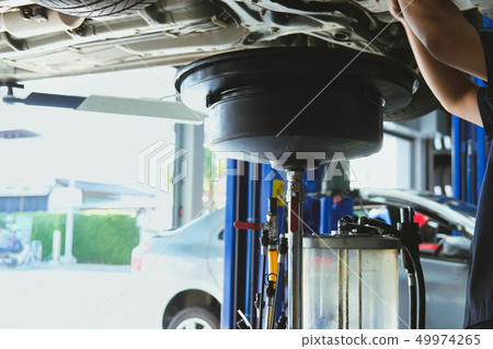 vehicle lift up by hydraulic for motor oil change & transmission inspection. changing engine oil in automobile repair service. maintenance & checkup in car workshop. vehicle lift up by hydraulic for motor oil change & transmission inspection. changing engine oil in automobile repair service. maintenance & checkup in car workshop. 49974265