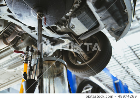 vehicle lift up by hydraulic for motor oil change & transmission inspection. changing engine oil in automobile repair service. maintenance & checkup in car workshop. vehicle lift up by hydraulic for motor oil change & transmission inspection. changing engine oil in automobile repair service. maintenance & checkup in car workshop. 49974269