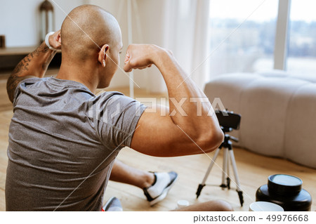 Young bodybuilder showing his nice biceps while making photo 49976668