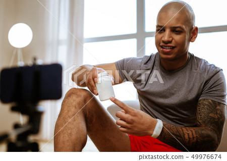 Young sportsman wearing smart watch recommending vitamins 49976674