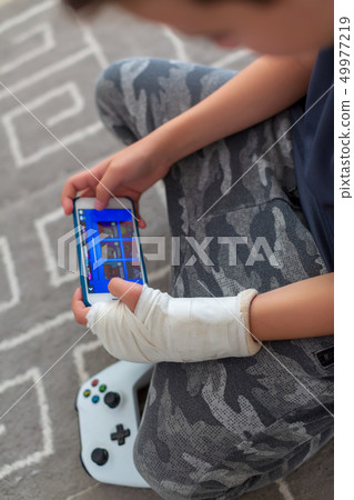 Portrait of teenage gamer boy playing video games on smartphone Portrait of teenage gamer boy playing video games on smartphone 49977219
