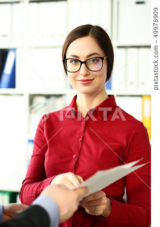 Smiling beautiful businesswoman wear glasses hold in arms financial papers Smiling beautiful businesswoman wear glasses hold in arms financial papers 49978909