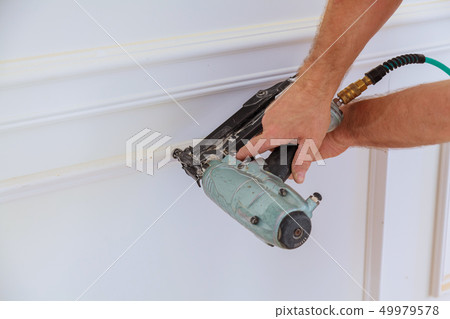 Installation of mouldings on the wall 49979578