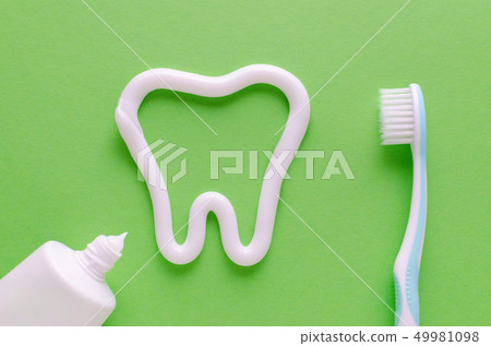 a tooth from toothpaste, teeth care concept, toothbrush on green background 49981098