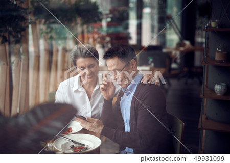 Elegant couple look with interest in mobile phone 49981099