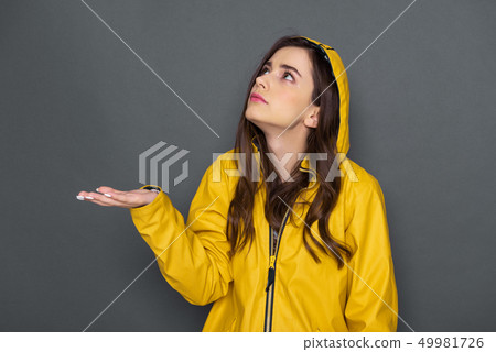 Waist up of pretty Caucasian girl dressed in yellow raincoat in studio 49981726