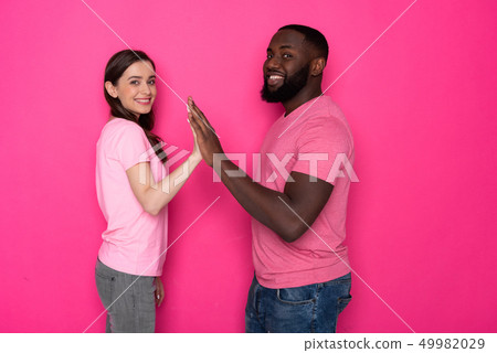 Waist up of smiling interracial couple looking at camera in studio 49982029