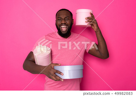 Screaming happy African man keeping gifts and looking at camera in studio 49982083
