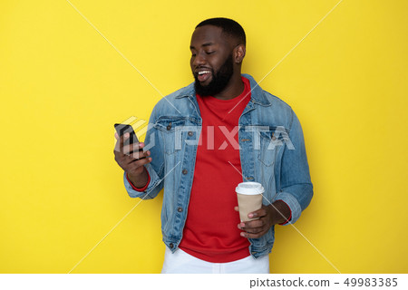 Waist up of smiling African man keeping cupholder and smartphone in arms Waist up of smiling African man keeping cupholder and smartphone in arms 49983385