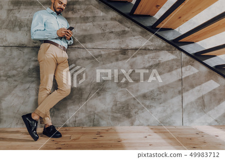 Cheerful man is messaging on phone indoors 49983712