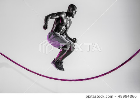 Young african-american bodybuilder training over grey background Young african-american bodybuilder training over grey background 49984866