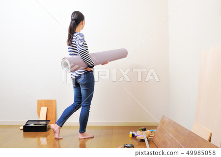 DIY woman putting a wallpaper 49985058