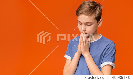 Cute concentrated boy praying, keeping eyes closed 49986188