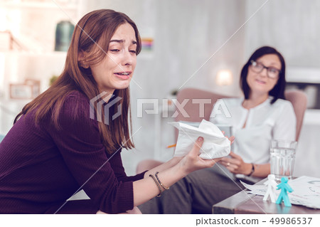 Crying upset young brown-haired lady going emotional during physiological therapy. Crying upset young brown-haired lady going emotional during physiological therapy. 49986537