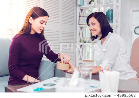 Dark-haired cheerful smiling psychologist cheering up a beautiful sad patient Dark-haired cheerful smiling psychologist cheering up a beautiful sad patient 49986568