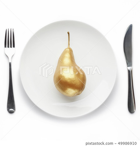 Golden pear on plate 49986910