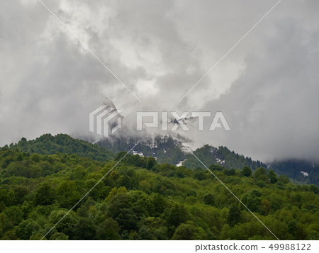 High mountains with snowy peaks in thick fog High mountains with snowy peaks in thick fog 49988122