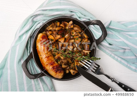 Cast-iron pan with fried sausage and mushrooms Cast-iron pan with fried sausage and mushrooms 49988650