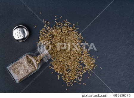Caraway seeds scattered on a black stone Caraway seeds scattered on a black stone 49989075