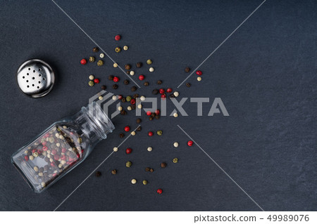 Different chilli pepper scattered on a black stone 49989076