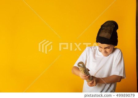 Boy shoots a confetti into the air against a yellow background 49989079