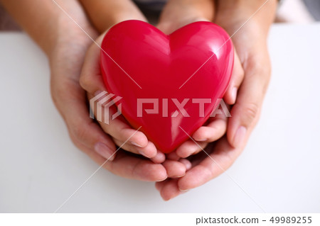 Woman and kid hold red toy heart in arms Woman and kid hold red toy heart in arms 49989255