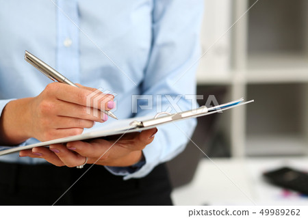 Female arm in suit hold silver pen and pad 49989262