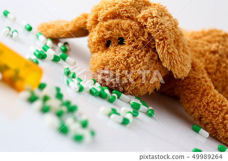 Teddy bear lie with big pile of tablets Teddy bear lie with big pile of tablets 49989264