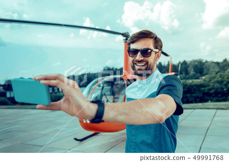 Contented short-haired man in stylish outfit making selfie 49991768