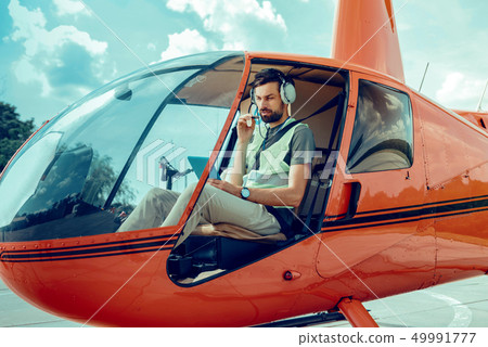 Serious professional guy in protective headphones and bright jacket Serious professional guy in protective headphones and bright jacket 49991777