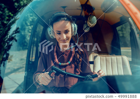 Joyful appealing woman wearing special headphones while being helicopter pilot 49991888