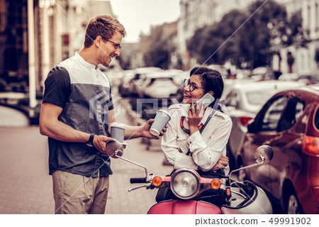 Joyful nice man offering coffee to his girlfriend Joyful nice man offering coffee to his girlfriend 49991902