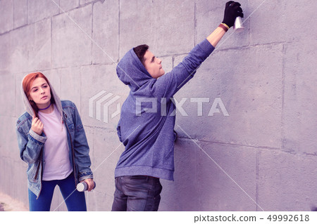 Extremal dark-haired guy using bottle of spray paints 49992618