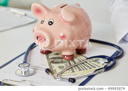 Funny piggybank standing on clipboard with document Funny piggybank standing on clipboard with document 49993874