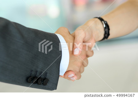 Businessman and woman shake hands as hello in office closeup 49994167