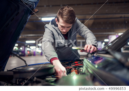 Man with phone in hand mending broken car with open hood. Man with phone in hand mending broken car with open hood. 49996853