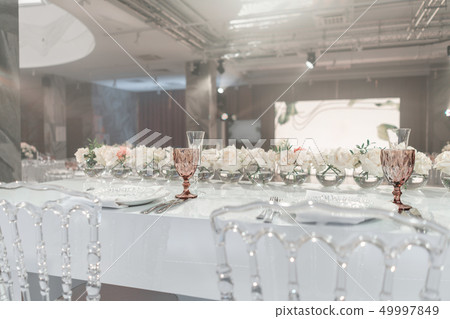The table of the newlyweds. Small flower arrangements in ball glass vases. Interior of restaurant 49997849