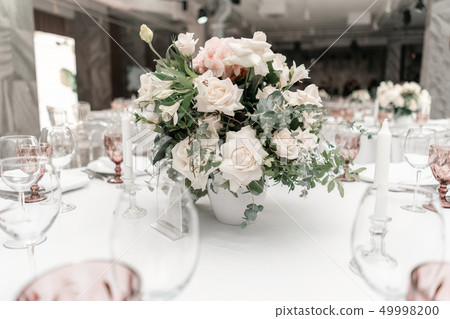 Flower arrangement in the center of the table. Interior of restaurant for wedding dinner, ready for 49998200
