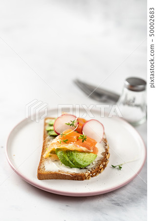 Vegatarian toast with avocado, radish and salmon. 50002683