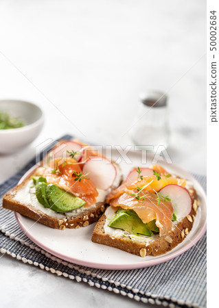 Tasty toasts with avocado, radish and salmon. Tasty toasts with avocado, radish and salmon. 50002684