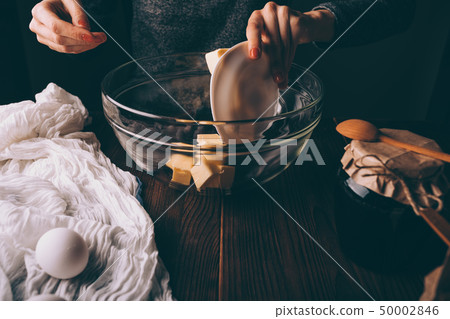 Female's hands adding diced butter to glass bowl Female's hands adding diced butter to glass bowl 50002846