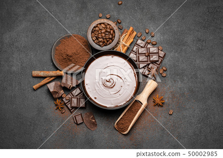 ceramic bowl of chocolate cream or melted chocolate and pieces of chocolate isolated on dark 50002985