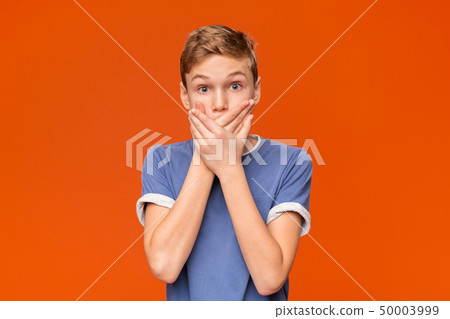 Portrait of stunned boy on orange studio background Portrait of stunned boy on orange studio background 50003999
