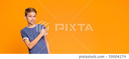 Emotional teen boy pointing aside at empty space 50004274