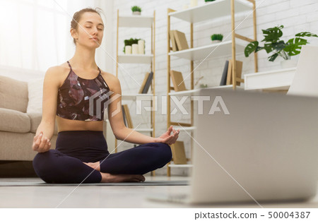 Meditating with laptop. Woman training yoga online 50004387
