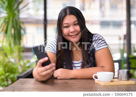 Beautiful overweight Asian woman relaxing at the coffee shop 50004575