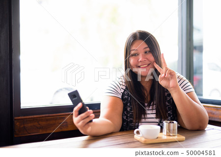 Beautiful overweight Asian woman relaxing at the coffee shop Beautiful overweight Asian woman relaxing at the coffee shop 50004581